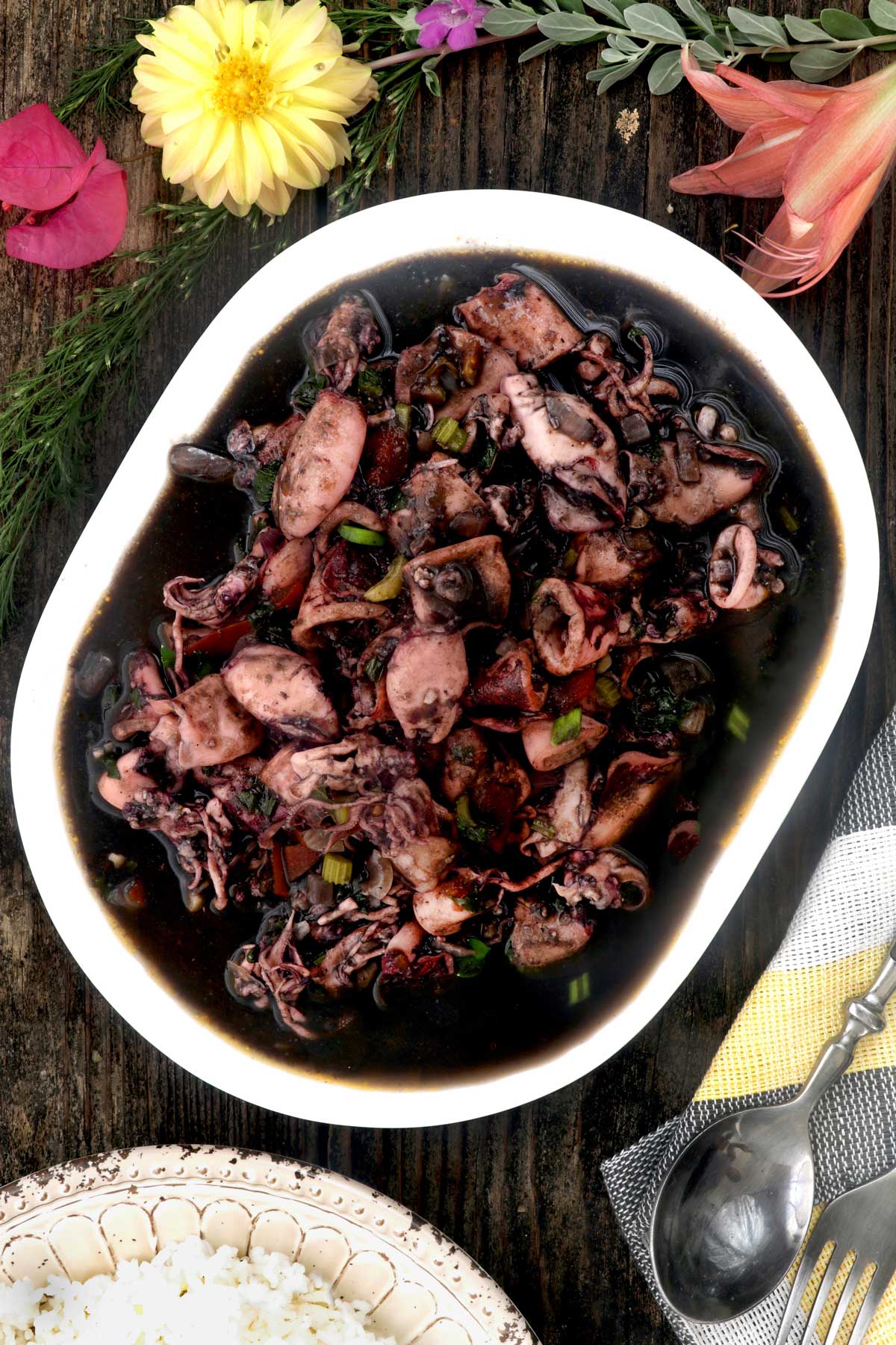 Freshly cooked adobong pusit in a serving platter served with rice.