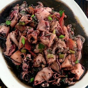 Adobong Pusit with tomatoes and celery on a plate.