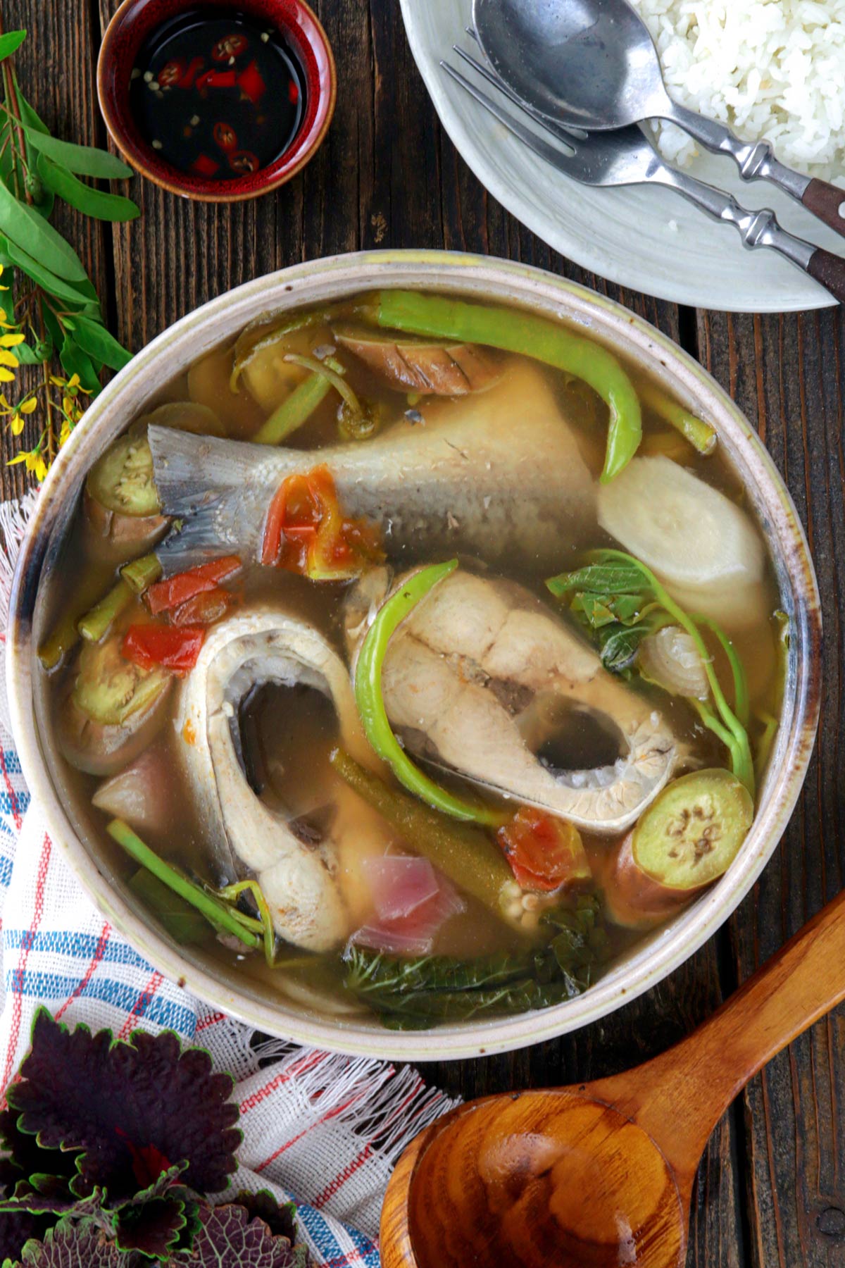 A hot bowl of sinigang na bangus served with steamed rice and spiced fish sauce.