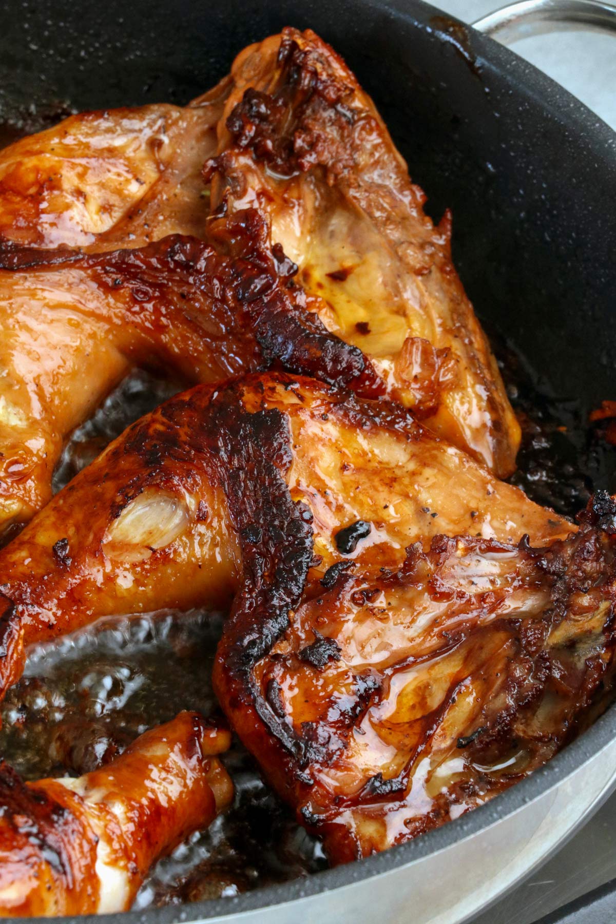 BBQ Chicken leg quarters in a frying pan.