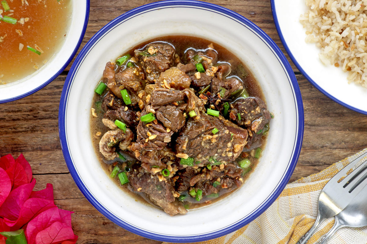 Beef Pares in a serving bowl with fried rice and beef broth on the side.