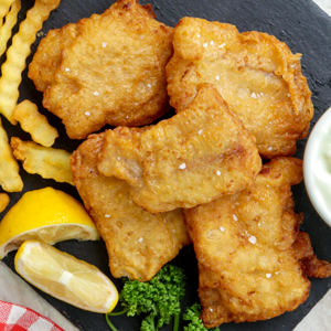 Crispy beer battered fish served with fries and lemon wedges.