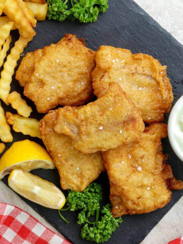 Crispy beer battered fish served with fries and lemon wedges.