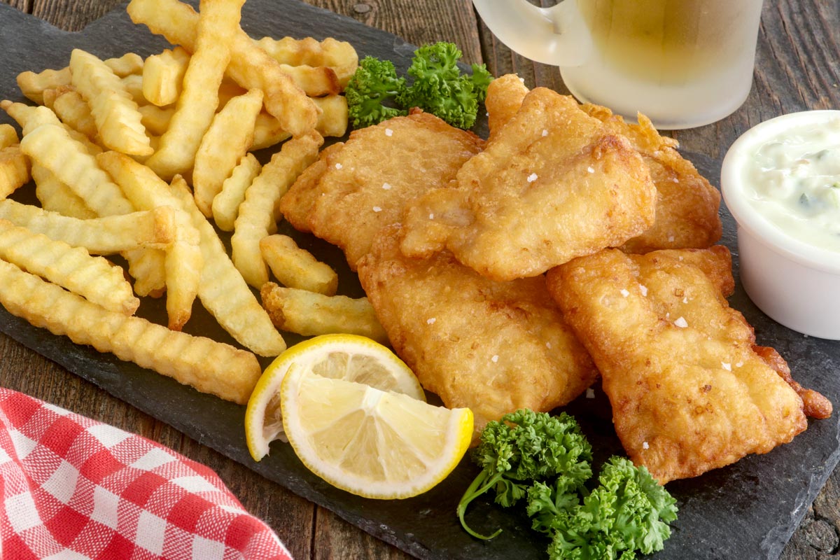 Beer battered fish served with fries and lemon wedges.