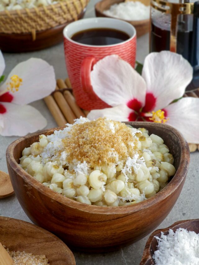 Binatog in a bowl topped with grated mature coconut and brown sugar.