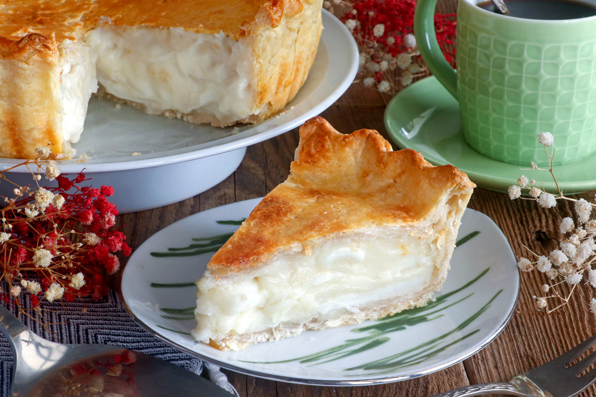 Slice of buko pie on a serving plate served with coffee.