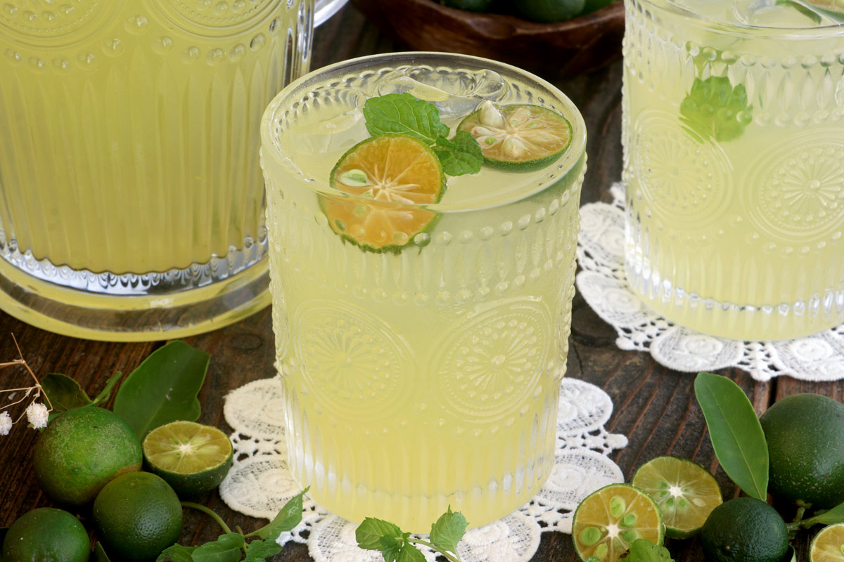 Calamansi juice in a glass served over ice with calamansi slices and mint leaves.