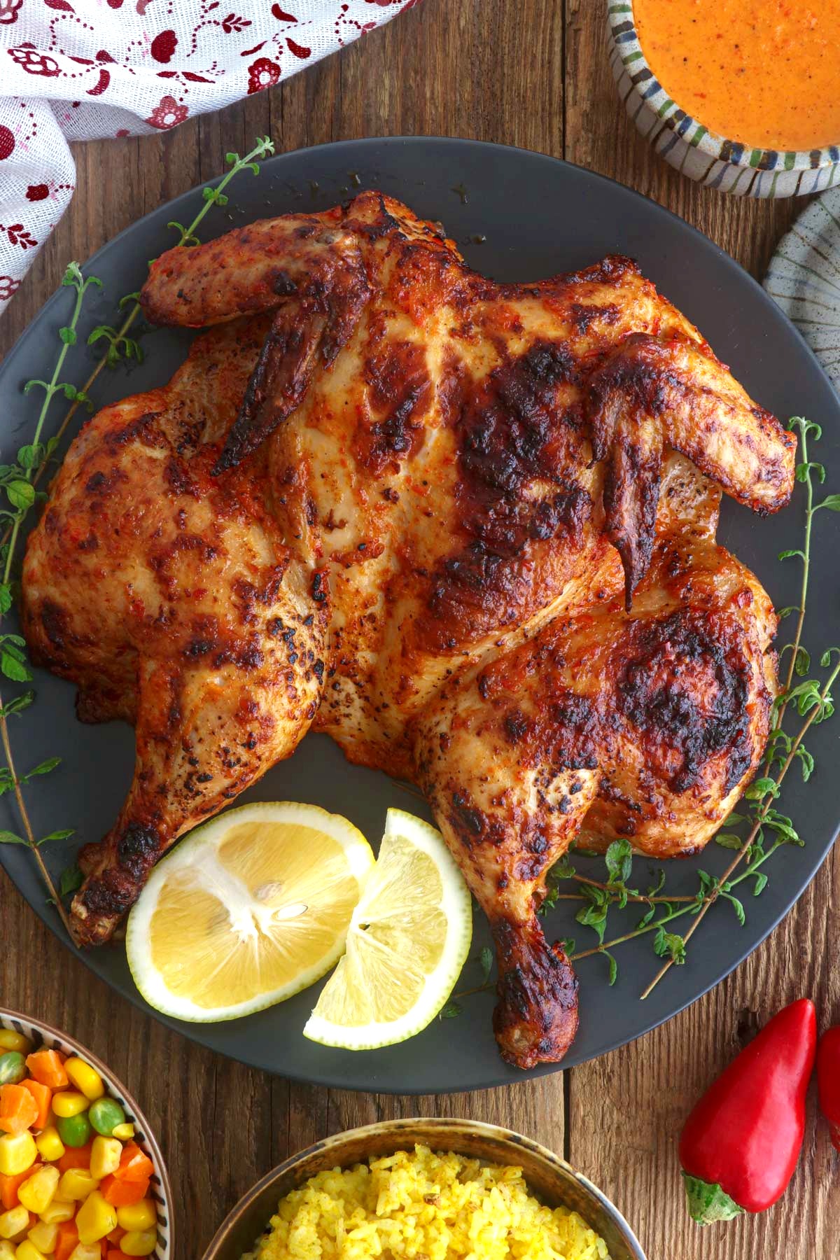 Chicken Peri peri on a serving plate with lemon wedges.