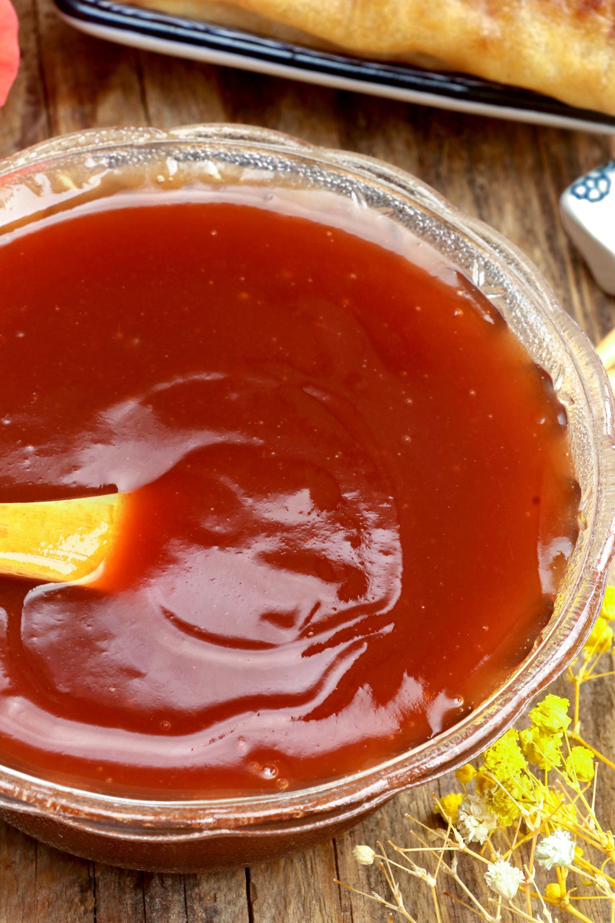 Homemade sweet and sour sauce in a bowl with serving spoon.