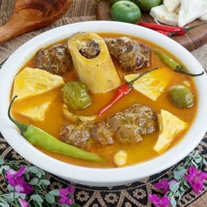 Kansi in a serving bowl made with beef shanks, green jackfruit, batwan, and chilis.