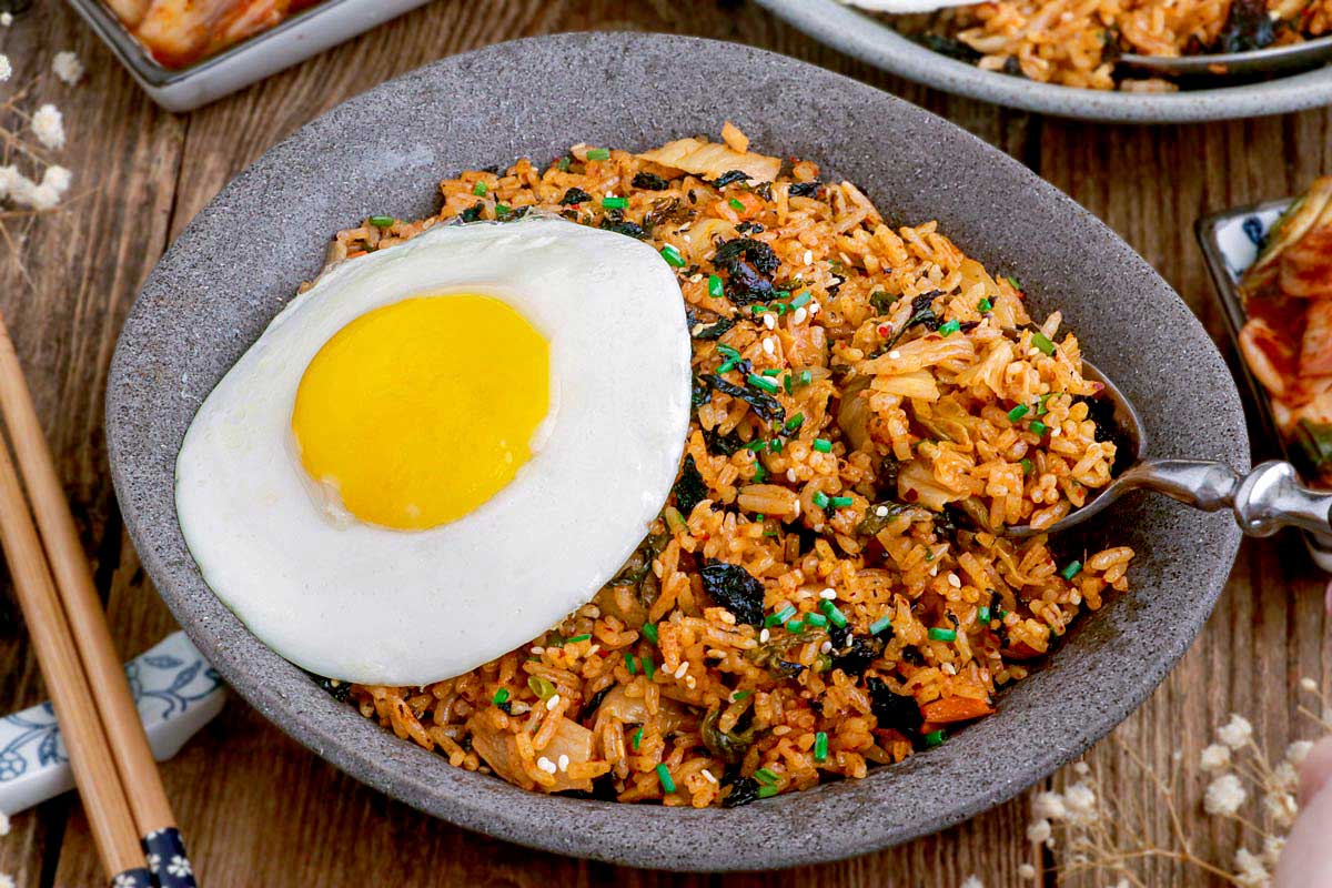 Kimchi fried rice topped with sunny-side up egg on a serving plate.