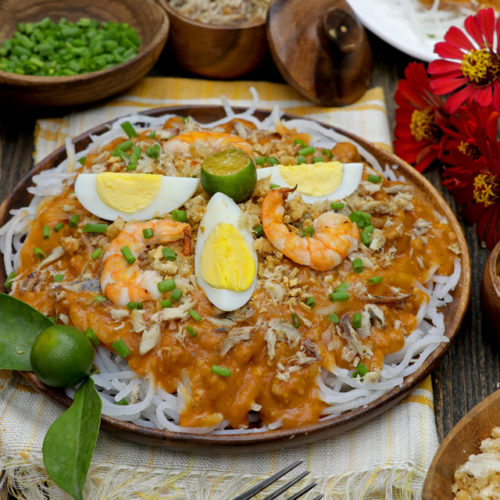 Pancit Luglug with hard-boiled eggs, shrimp, pork rind, and shredded smoked fish