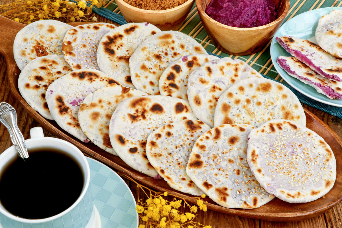 Homemade Piaya on a serving plate with classic and ube fillings served with coffee.