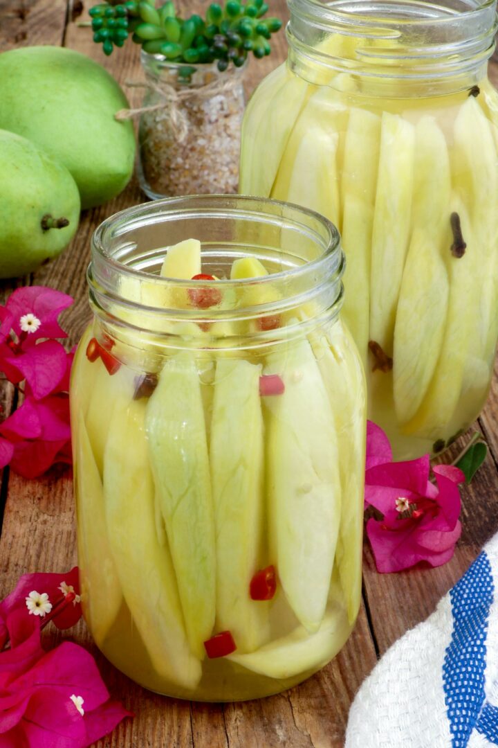 Pickle Mangoes in jars with chopped chili, peppercorns, and cloves.