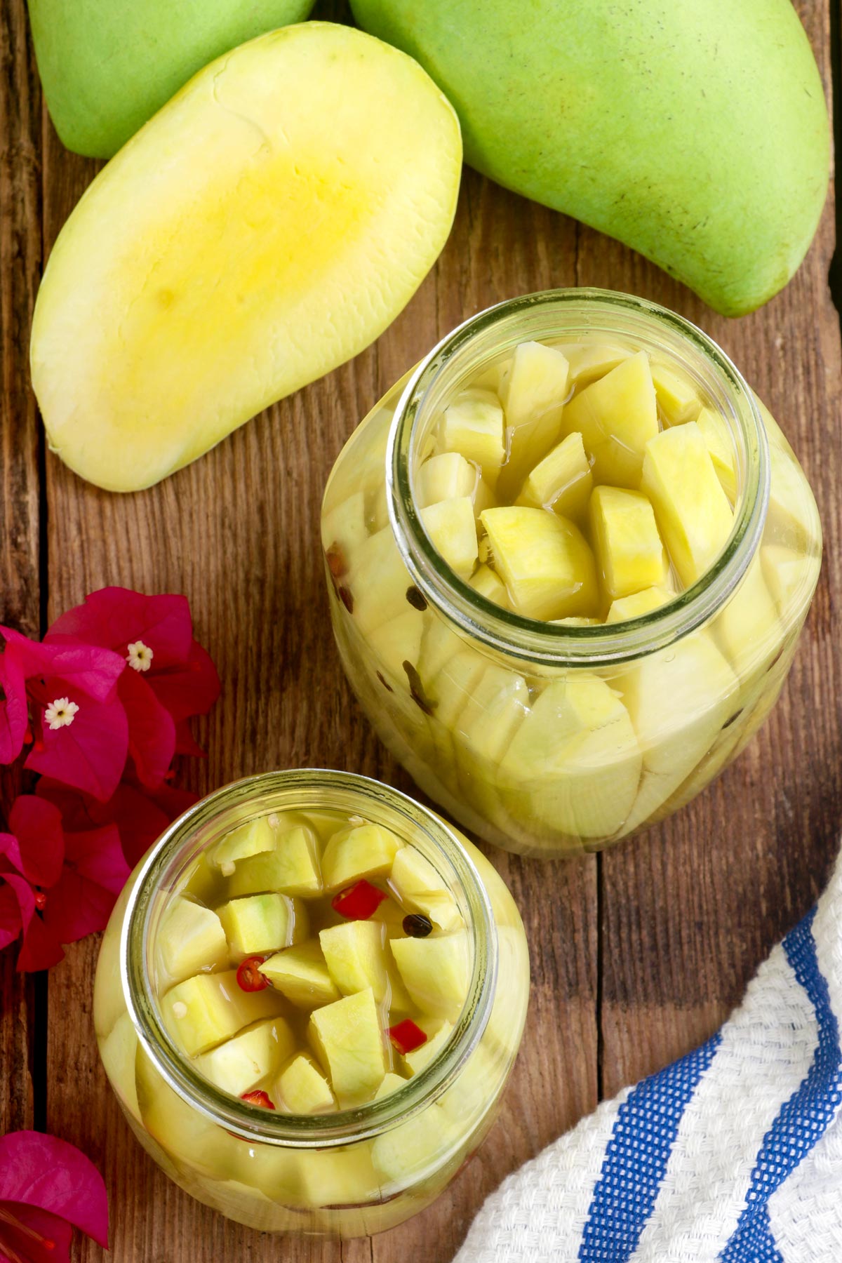 Pickled Mangoes in sterilized jars made with almost ripe green mangoes, chopped red chili and whole peppercorns. 