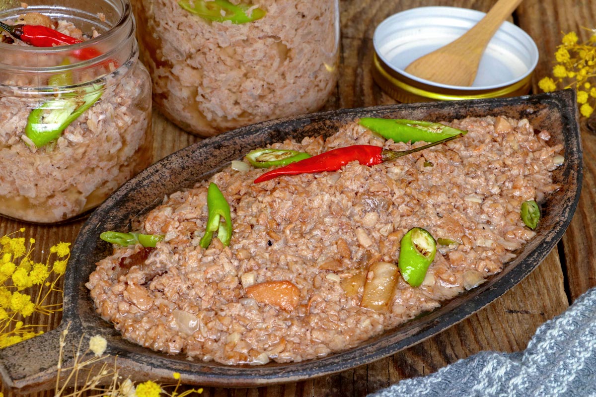 Sinantolan on a serving plate and jars with green and red chilis.